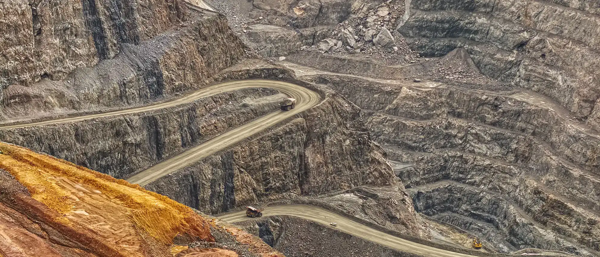 Aerial view of a large benched open-pit mine with winding haul roads
