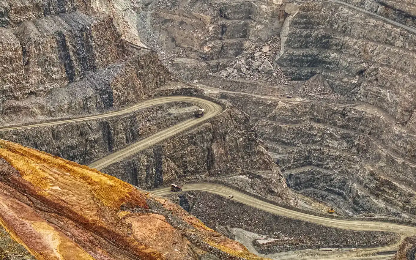 Aerial view of a large benched open-pit mine with winding haul roads